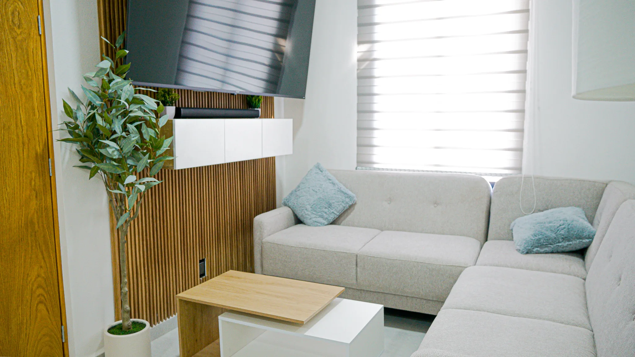 Sala con sofá seccional, mesa de centro y televisión en el departamento muestra de Sendas