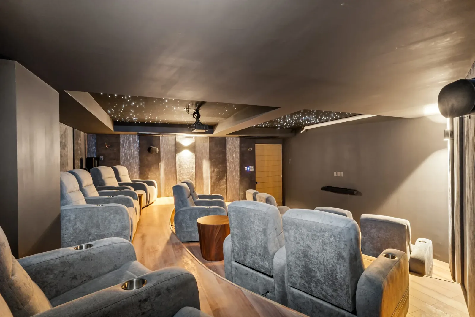 Sala de cine privada con butacas reclinables grises y techo con luces tipo estrellas