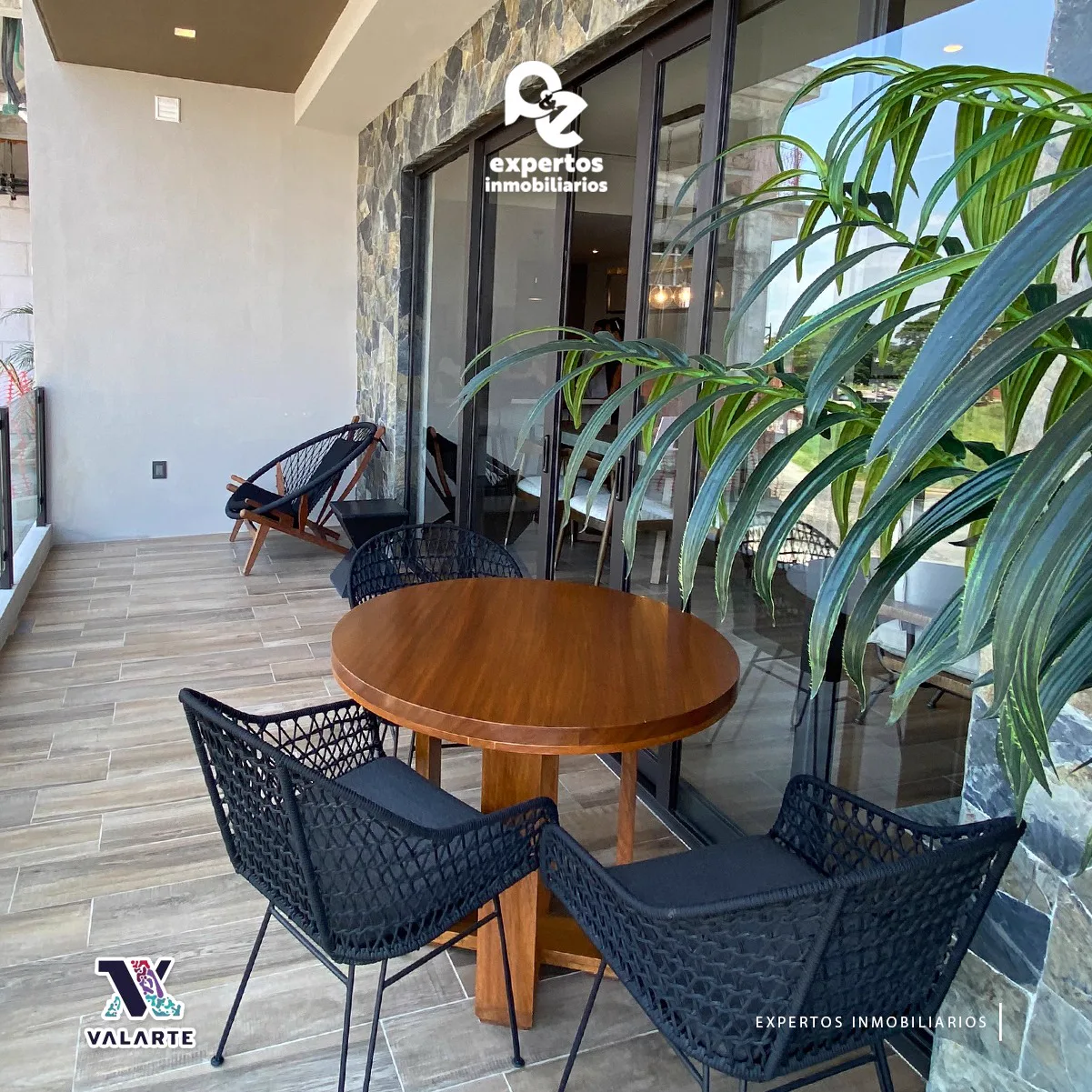 Terraza con mesa redonda de madera y sillas tejidas