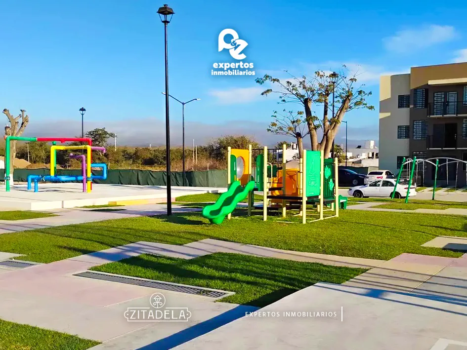 Área de juegos infantiles con resbaladilla y estructuras de colores